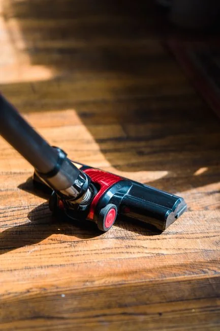 services-05 a-woman-in-a-green-shirt-and-black-gloves-vacuuming-a-gray-ottoman-5txz228u4eo